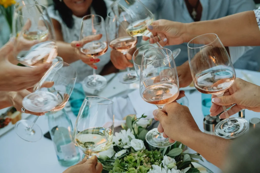 many hands toasting with glasses of wine at a celebration
