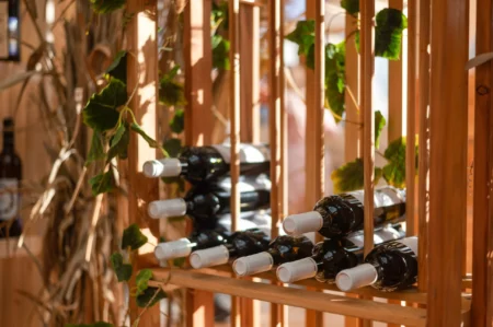 bottles with wine lie on a wooden rack on a summer