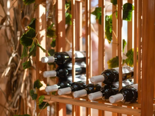 bottles with wine lie on a wooden rack on a summer
