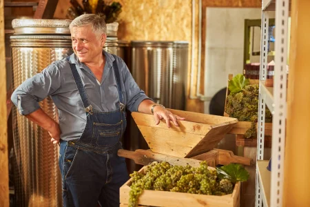 joyful winemaker smiling and posing inside the wine cellar; how to make wine