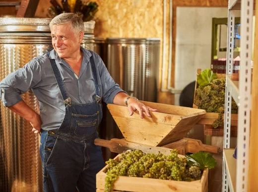 joyful winemaker smiling and posing inside the wine cellar; how to make wine