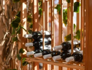 bottles with wine lie on a wooden rack on a summer day