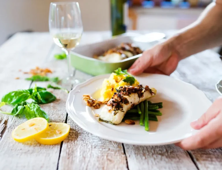 man serving fish with white wine