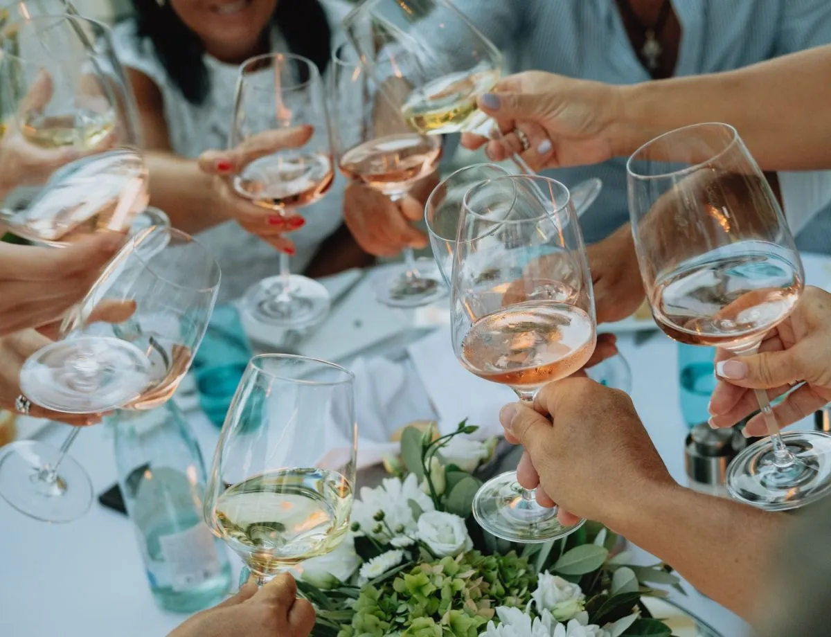 many hands toasting with glasses of wine at a celebration